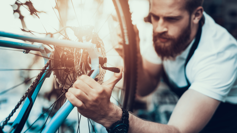 Mann som reparer en sykkel